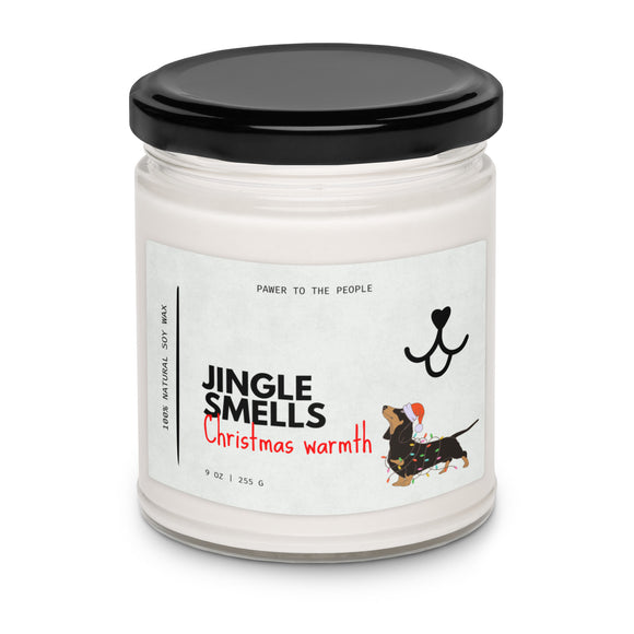Candle jar labeled 'Jingle Smells Christmas warmth' with a black lid on a white background. Features a Dachshund dog wearing a Santa hat and wrapped in colorful string lights.